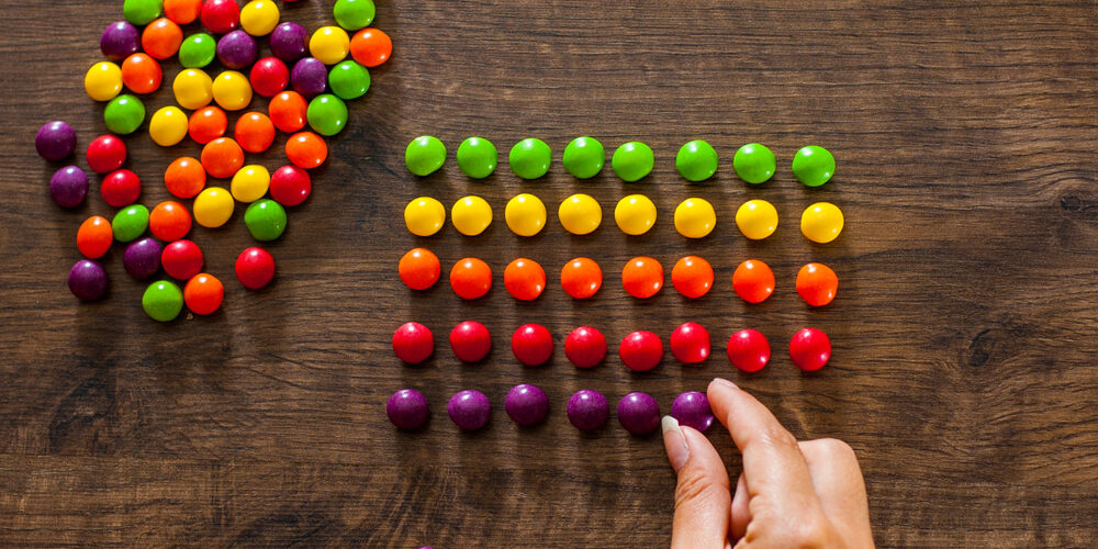 Woman's,Hand,Collects,Even,Row,Of,Colorful,Candies,On,A